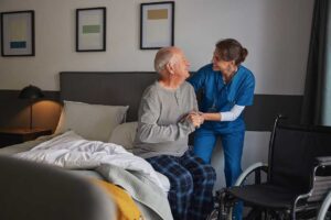 Older adults sharing a meal in a bright assisted living dining room with a caregiver nearby.